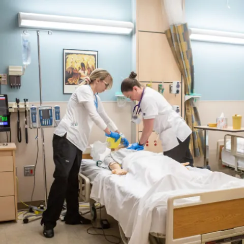 Two nursing students taking care of a mannequin patient